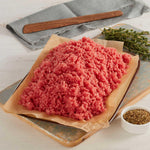Carne Molida Magra de Res marca Sagal sobre una tabla de cortar adornada con tomillo y especias