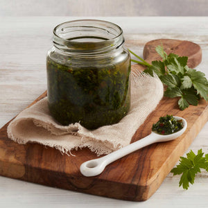 Frasco de Chimichurri Marca Sagal sobre Tabla de Cortar y Especias