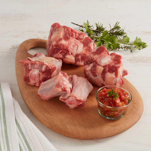 Cinco Trozos de Cola de Res Marca Sagal Crudos Sobre Tabla de Cortar y Adornados con Especies