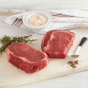 2 Piezas de Entrecôte de Res crudos sobre tabla de cortar adornados con especias