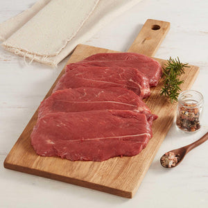 Cuatro Escalopes de Res Crudos Sobre Tabla de Cortar adornados con especias