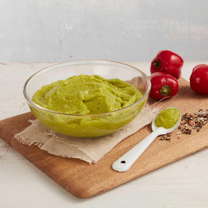 Porción de Guacamole Marca Sagal Presentado en un Plato sobre una tabla y decorado con pimientos