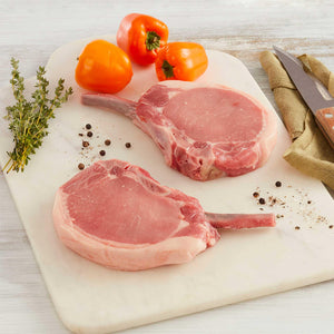 rib eye de cerdo marca sagal en una tabla de cortar adornado con tomates tomillo y cuchillo de cortar