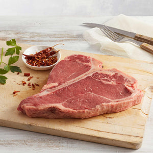 T-Bone de Res Crudo Marca Sagal sobre tabla de cortar adornado de especias